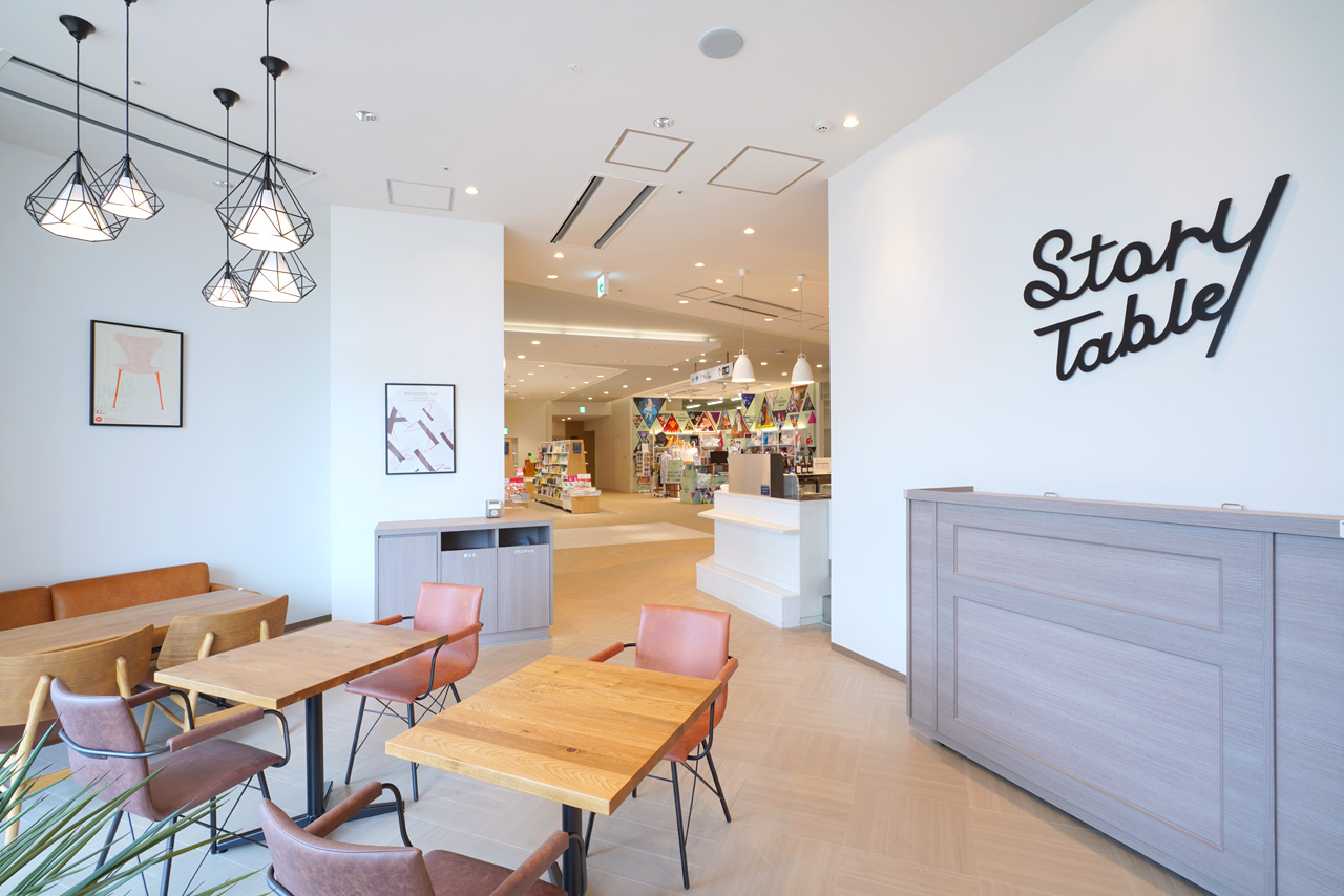 カフェの席。白い壁面にSTORY TABLEのロゴ