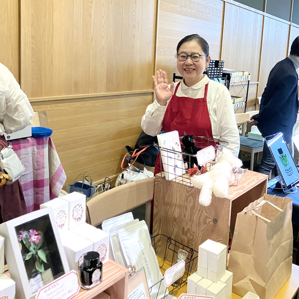 会場内でバイヤー岡﨑が手を振っている