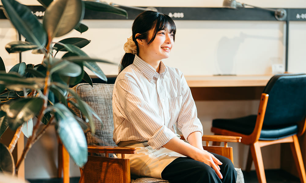 インタビューの様子、観葉植物と椅子と横田さん
