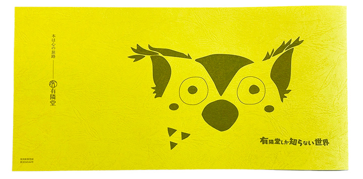 R.B.ブッコロー柄の文庫カラーカバー。黄色の紙に、ブッコローの顔・ゆうせかロゴ・“本は心の旅路”が印刷されている