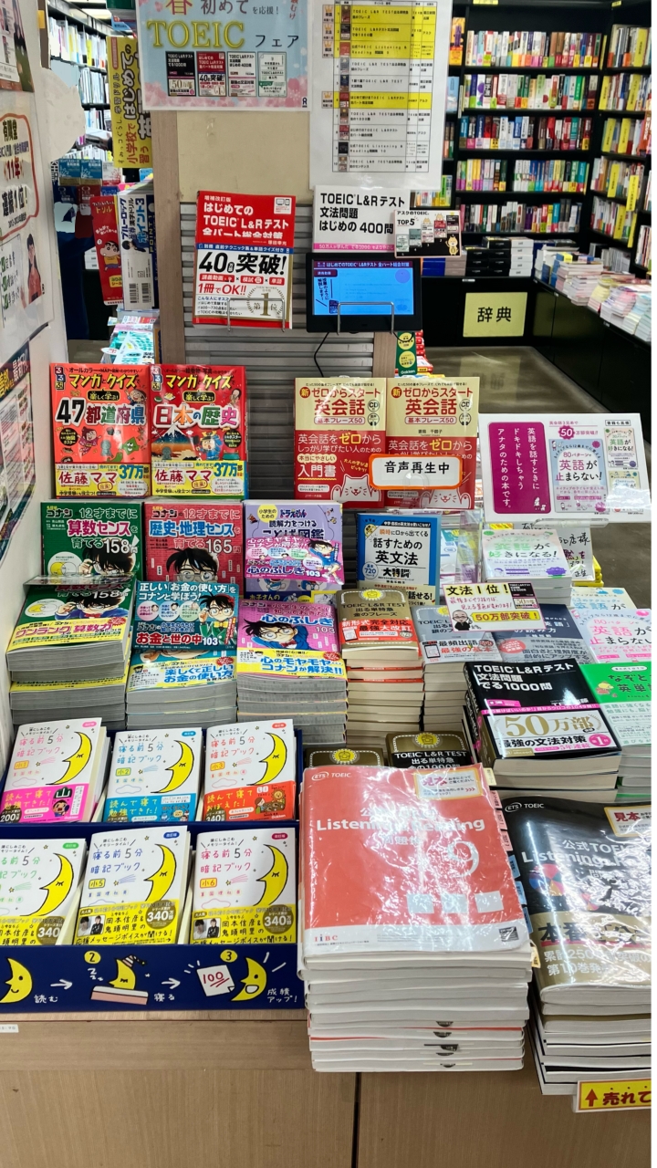英語の書籍がテーブルに並び、小型ディスプレイで映像が流れている