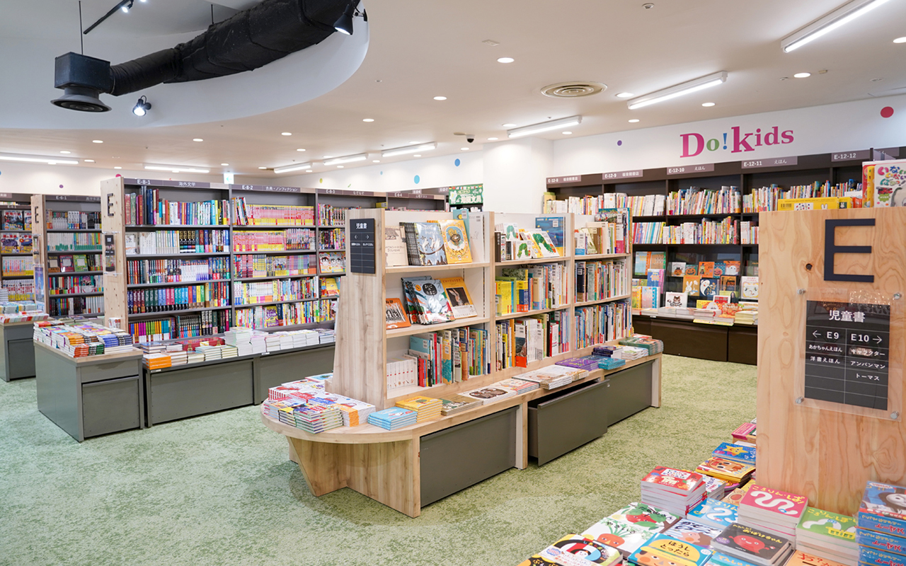 子どもの本・知育玩具コーナー「Do!kids」の、絵本の棚。毛足の長いカーペットの床に、丸くて背の低い書棚。