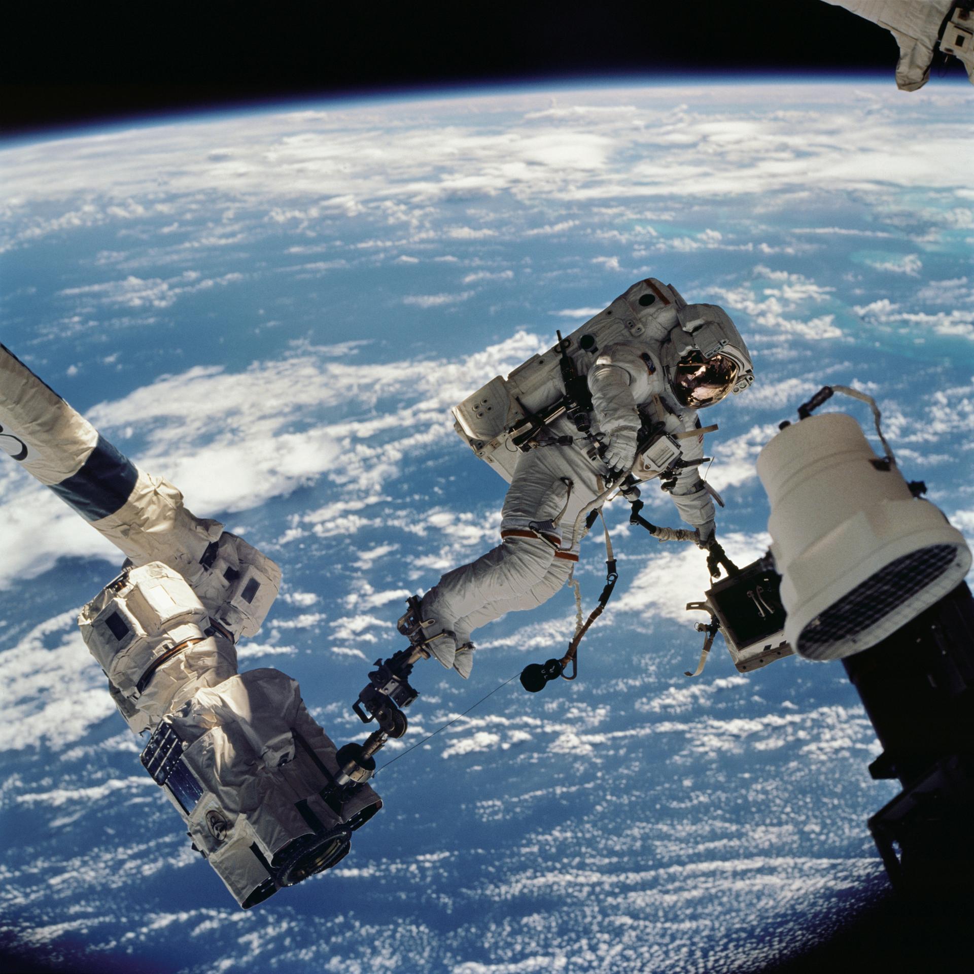 地球を背景に遊泳中の宇宙飛行士の写真