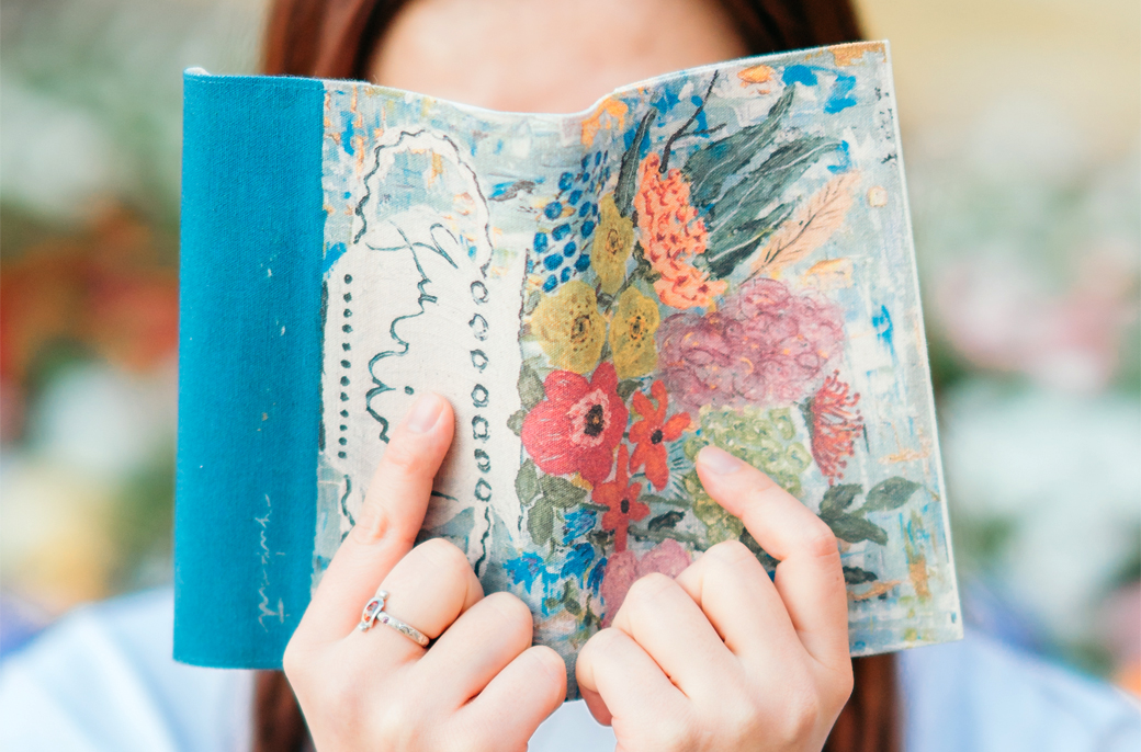 ブックカバーの背中側を見せている女性の写真